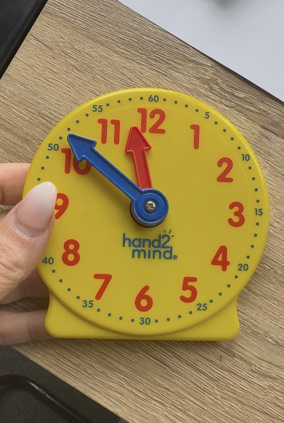 Yellow analogue teaching clock showing how children learn to tell the time through patterns and fractions.